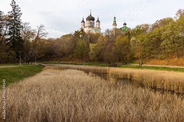 Obraz Orthodox church overlooking autumn park with dry grass and pond