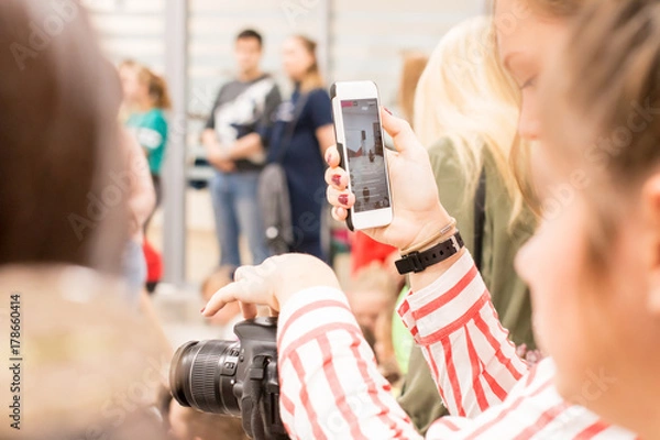 Fototapeta The girl shoots on the camera and takes pictures on the phone