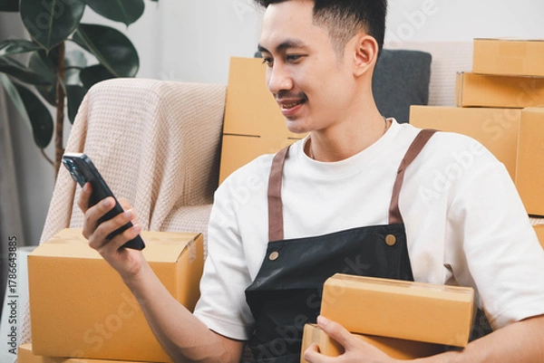 Fototapeta Startup small business owner packing boxes for online customer delivery. Entrepreneur managing e-commerce orders, shipping parcels, and running home-based business operations from home office.