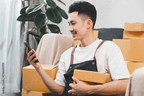 Fototapeta Startup small business owner packing boxes for online customer delivery. Entrepreneur managing e-commerce orders, shipping parcels, and running home-based business operations from home office.