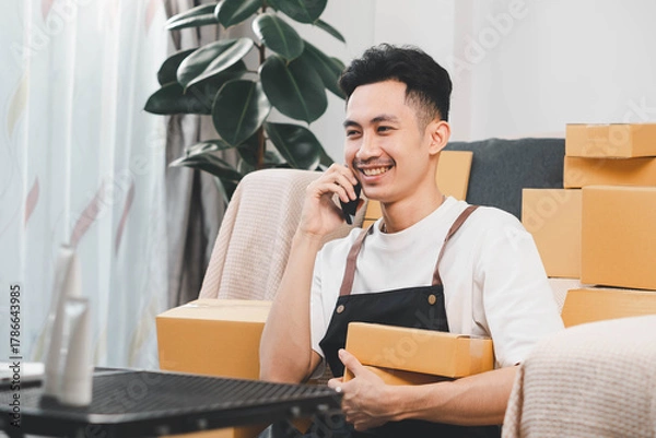 Fototapeta Startup small business owner packing boxes for online customer delivery. Entrepreneur managing e-commerce orders, shipping parcels, and running home-based business operations from home office.