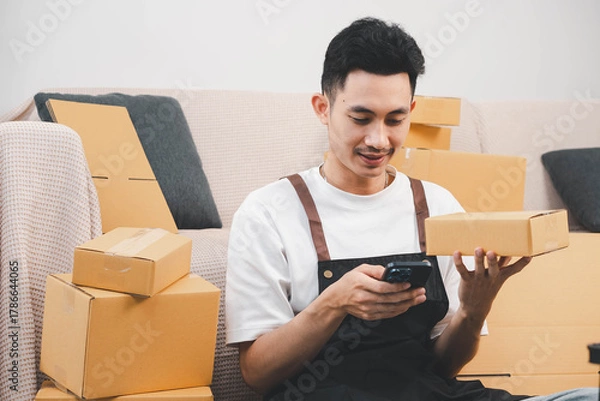 Fototapeta Startup small business owner packing boxes for online customer delivery. Entrepreneur managing e-commerce orders, shipping parcels, and running home-based business operations from home office.