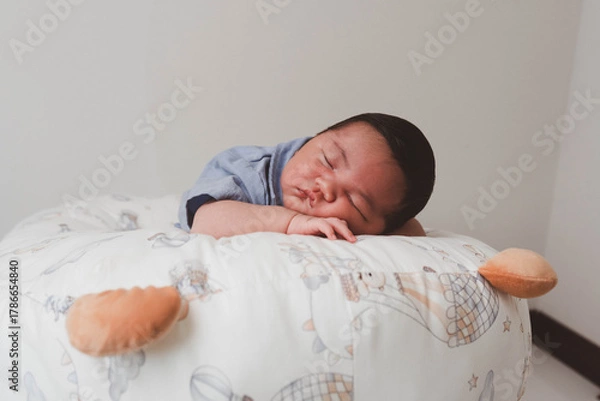 Fototapeta Cute newborn baby boy sleeping peacefully in white crib and soft nest. Close-up of infant resting on bed, symbolizing childhood innocence, comfort, and family love. Perfect for baby care themes.