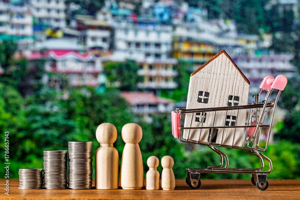 Fototapeta Small wooden toy house in shopping cart, stack of coins and figures of people on nature background. Concept of save money for purchase or construction of home, mortgage and real estate investment