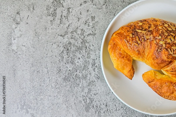 Fototapeta Top view of one cheese croissant on white plate. close up. grey or gray cement on the background. High angle, above, flat lay. half. copy space, empty, free, negative, text, design.
