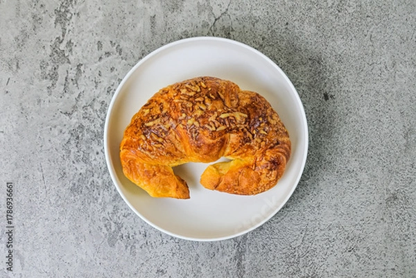 Fototapeta Top view of one cheese croissant on white plate. close up. grey or gray cement on the background. High angle, above, flat lay.