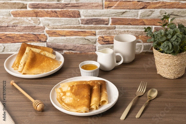 Fototapeta Delicious golden crepes served with honey and sauce on a rustic wooden table in a cozy setting
