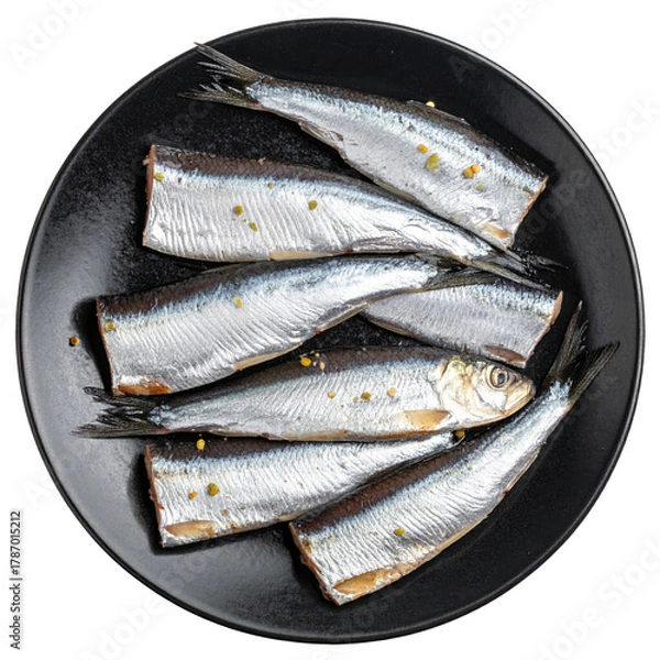 Fototapeta A pile of crispy fried sprat fillets on a dark plate, a simple and delicious small fish appetizer or main course, isolated on white background