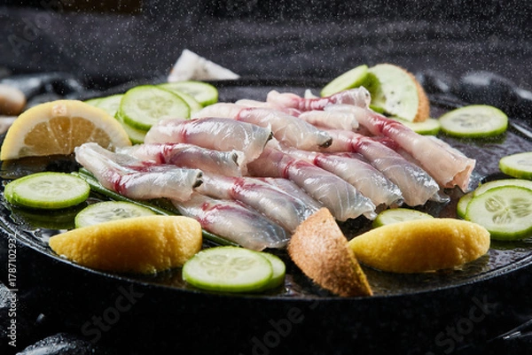 Fototapeta Arrange the glistening, white slices of fresh fish on a black round porcelain plate.