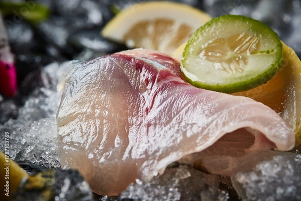 Fototapeta Arrange the glistening, white slices of fresh fish on a black round porcelain plate.