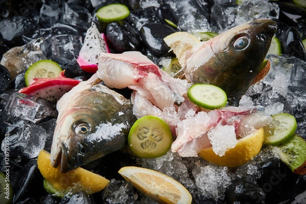 Fototapeta Arrange the glistening, white slices of fresh fish on a black round porcelain plate.