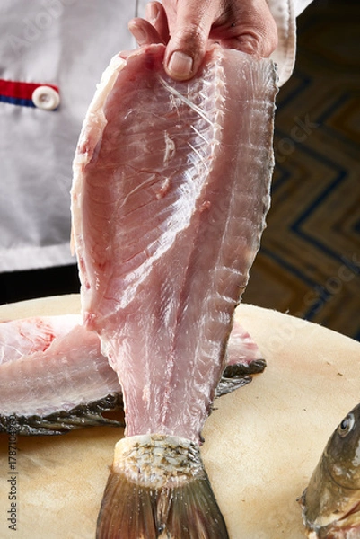 Fototapeta On a white cutting board, the chef demonstrates his exquisite knife skills in cutting and slicing sashimi and fresh fish.