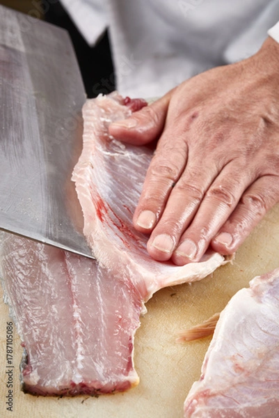 Fototapeta On a white cutting board, the chef demonstrates his exquisite knife skills in cutting and slicing sashimi and fresh fish.