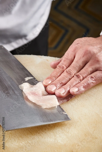 Fototapeta On a white cutting board, the chef demonstrates his exquisite knife skills in cutting and slicing sashimi and fresh fish.