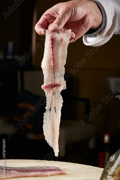 Fototapeta On a white cutting board, the chef demonstrates his exquisite knife skills in cutting and slicing sashimi and fresh fish.