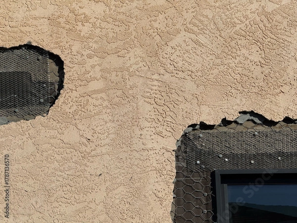 Fototapeta Close-up view of exterior stucco wall under repair with exposed wire lath and nails showing structural layers of cement and insulation on a residential building facade