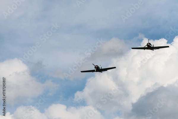 Fototapeta Two Propeller Aircraft Flying in Formation Through Cloudy Sky