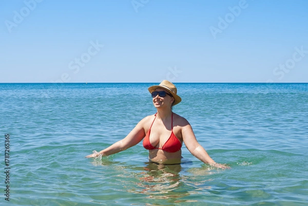 Fototapeta Happy woman in a hat and sunglasses enjoying the sea and sun