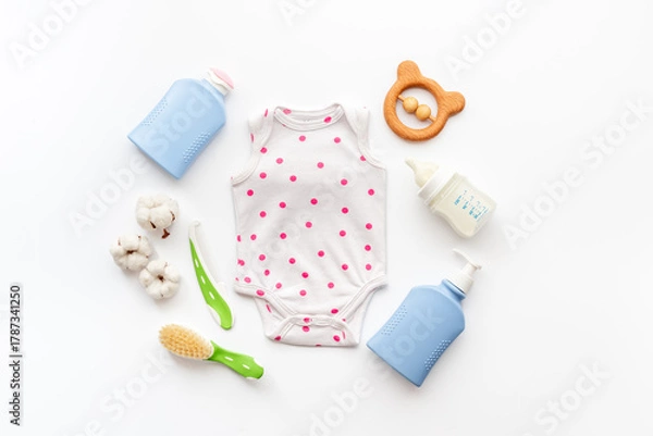 Fototapeta Set of baby hygiene cosmetic products - shampoo and soap with a comb. Eco friendly accessories - bodysuit and wooden toys with bottle of milk on white background, top view