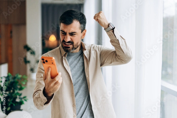 Obraz Frustrated man expressing anger while using smartphone