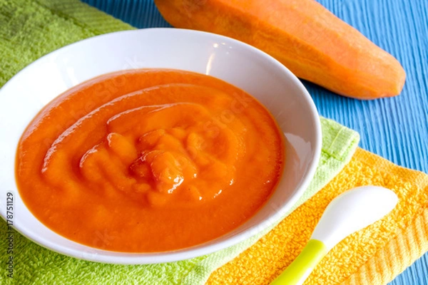 Obraz puree of baby carrot Apple on a wooden table spoon saucer white green pacifier napkin orange