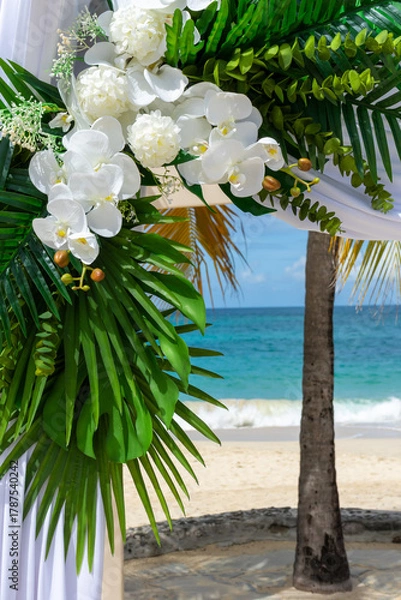 Obraz Bathed in sunlight, the wedding pagoda blooms with white orchids and silk, overlooking the turquoise Caribbean Se