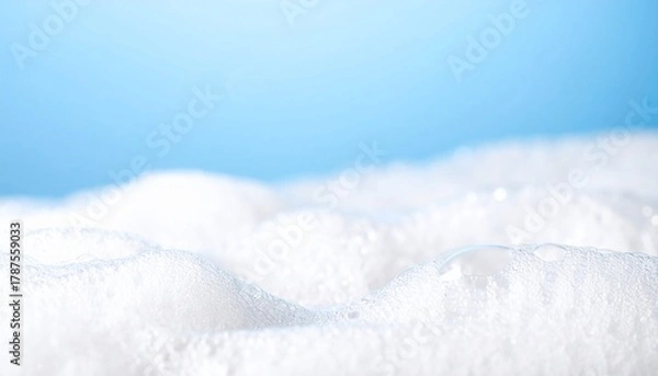 Fototapeta Close-up of fluffy white soap bubbles on a bright blue background clean texture