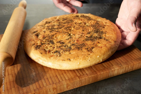 Fototapeta A chef prepares focaccia on a wooden board, close-up. Food preparation.