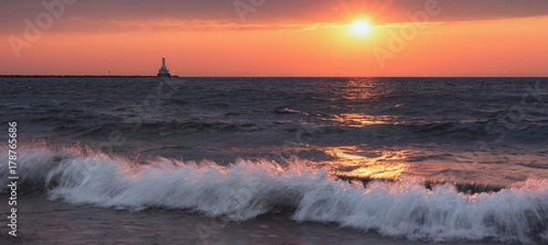 Fototapeta Sunset Waves Crashing. Wide Tranquil Beach under a Fiery Orange Sky. Lake Superior Seascape. Natural Beauty Background with Oceans of Copy Space.