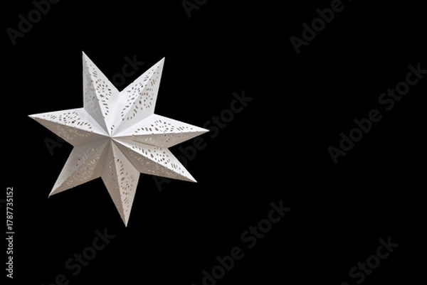Fototapeta White decorative star on black background. Isolated white decorative star with cutout patterns on a black background. Elegant geometric Christmas ornament, festive minimalist decoration.