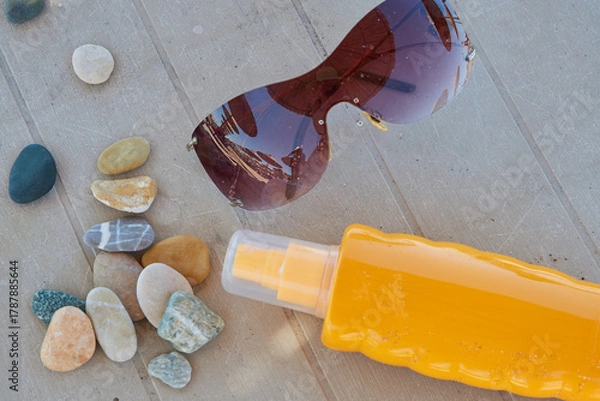 Fototapeta Top view of sunglasses, sunscreen bottle on sun lounger surface