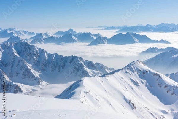 Fototapeta Majestic snow-capped peaks above a sea of clouds under blue sky