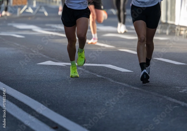 Obraz runners in a marathon showing close up on athletic legs and running shoes on city street