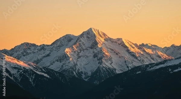 Fototapeta Serene landscape of giant snow covered mountain peaks illuminated by warm golden sunlight during evening twilight hour, nature, horizontal, vista