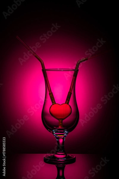 Fototapeta Romantic concept with heart-shaped straw in an empty glass on crimson background – symbol of love, relationship, and togetherness. Minimalistic Valentine’s Day still life.