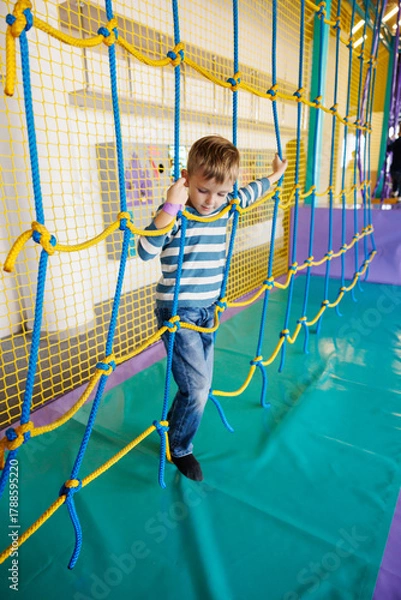 Fototapeta Child Enjoying Rope Climbing Adventure in Indoor Playground