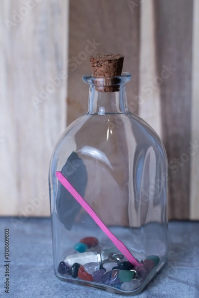 Fototapeta Gem stones or healing crystals in a square shaped glass jar that has a cork top.