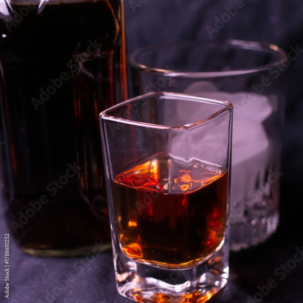 Fototapeta Brown liquor and various sized glasses to enjoy it from. 