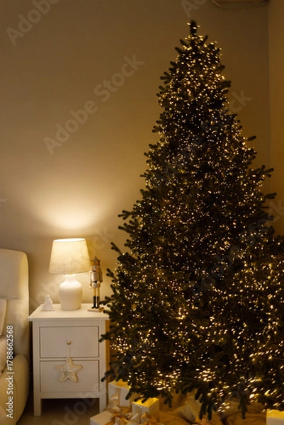 Obraz Cozy bedroom interior with warm fairy lights, soft pillows, and a cup of coffee on a tray. Relaxing winter morning or holiday atmosphere in a comfortable home setting