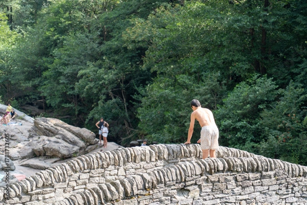 Fototapeta Lavertezzo, Switzerland - August 14, 2025: The charming village in Ticino, Switzerland, is famed for its crystal-clear Verzasca River, where people enjoy a refreshing dip in the cool water.