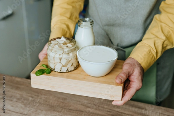 Fototapeta Close up of male hands holding wooden tray with tofu, yogurt and milk