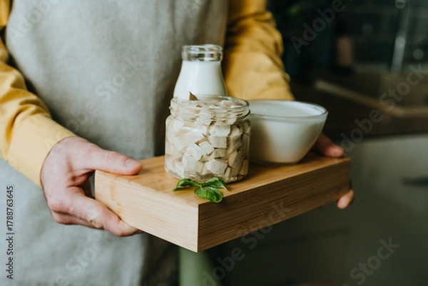 Fototapeta Close up of man holding wooden tray with tofu, yogurt and milk