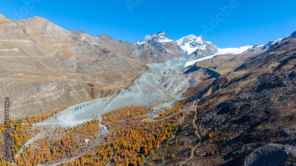 Fototapeta A drone view above Zermatt reveals the stunning Matterhorn region with its famous lakes, golden larches, and a deep blue autumn sky in perfect harmony.