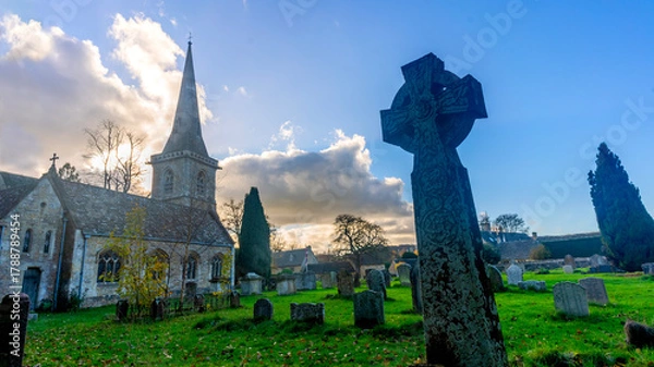 Obraz Historic church with ancient cross on green graveyard lawn