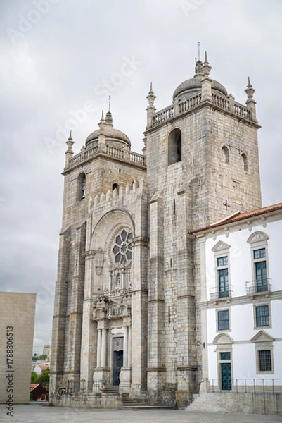 Fototapeta Historic Porto Cathedral façade rises against moody sky, Romanesque-Gothic stonework inviting heritage exploration, ideal for Portugal travel promos.