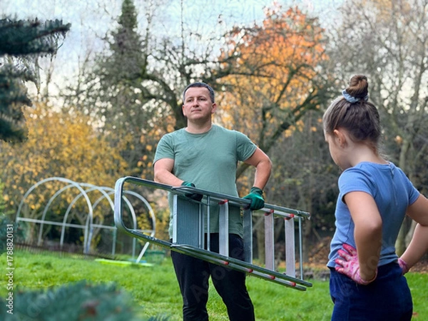 Fototapeta Man and girl in garden with ladder
