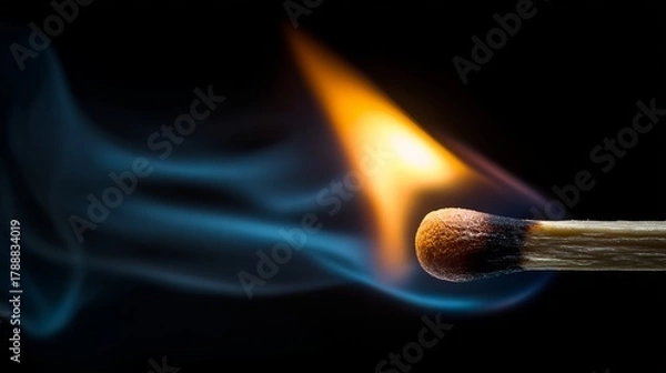 Fototapeta Dramatic close-up of a burning match igniting with vibrant orange flame and wisps of blue smoke against a dark background
