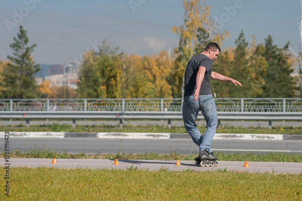 Obraz A Caucasian man rollerblades around the slalom course.