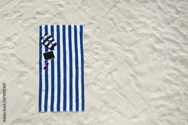 Obraz Top view of sandy beach with towel frame and summer accessories. Background with copy space and visible sand texture.