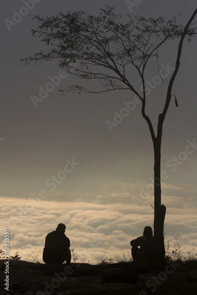 Fototapeta silhouette of a man sitting on ground with view sea mist on morning mountain